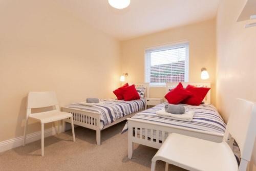 a bedroom with two beds and a chair and a window at Summerfold in Warkworth
