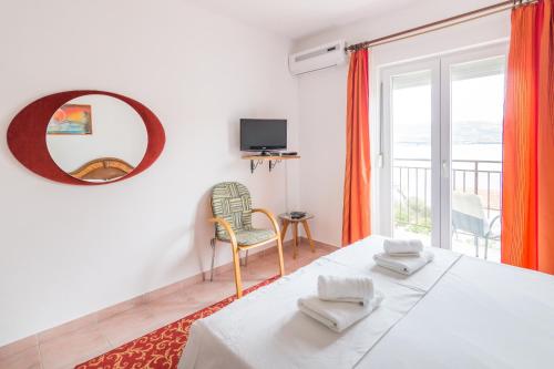 Schlafzimmer mit einem Bett und einem Spiegel sowie einem Balkon in der Unterkunft CHEAP apartment TANJA in Trogir