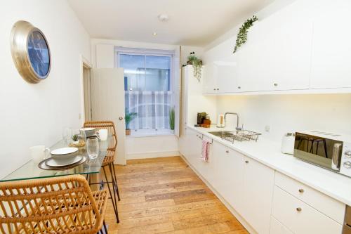 a kitchen with white cabinets and a table and chairs at Centrally Located Apartment - Pass the Keys in Lincoln