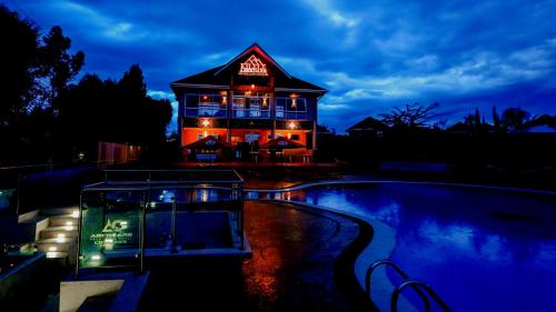 a building with a neon sign on it next to a swimming pool at Aberdare Prestige & Royal Cottages in Nanyuki