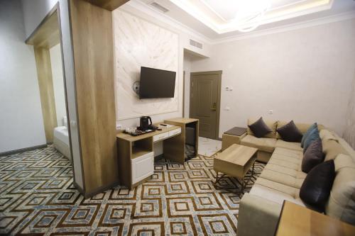 a living room with a couch and a tv at Khan Palace in Türkistan