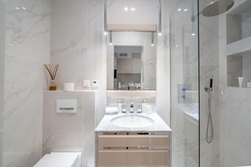 a white bathroom with a sink and a shower at Luxury Apartment - 150m to Palais des Festivals ( Cannes ) in Cannes