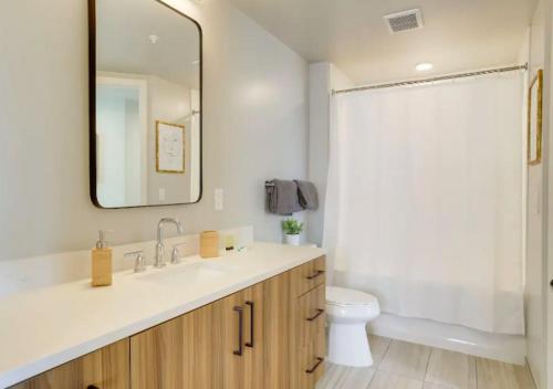 a bathroom with a sink and a toilet and a mirror at Wonderful 2BR Apartment At Clarendon With Gym in Arlington