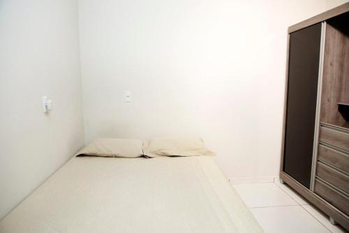 um pequeno quarto branco com uma cama e uma televisão em 102-FLAT-Espaço, conforto. É disso que você precisa! em Anápolis