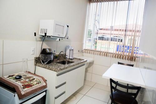 a small kitchen with a sink and a microwave at 102-FLAT-Espaço, conforto. É disso que você precisa! in Anápolis
