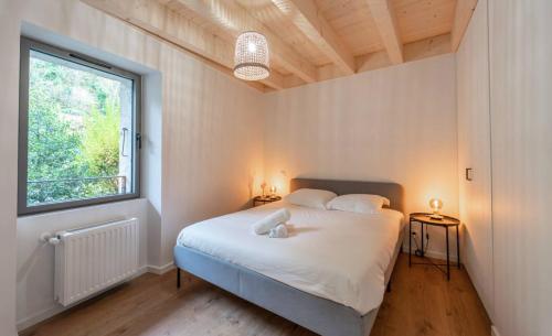 - une chambre avec un lit blanc et une fenêtre dans l'établissement Maison de Village - 291, à Duingt