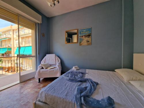 a bedroom with a bed and a chair and a window at [P.ZZA MARCONI] Bilocale per la vacanza al mare in Pietra Ligure