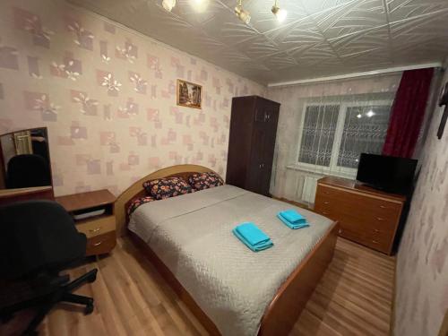 a bedroom with a bed with blue slippers on it at Jaukūs apartamentai miesto centre in Šiauliai