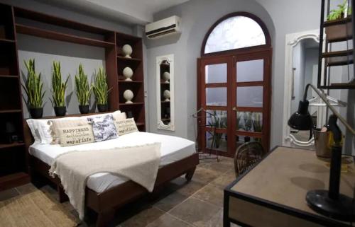 a bedroom with a bed and a desk with plants at AmazINN Places Rooftop and Jacuzzi in Panama City
