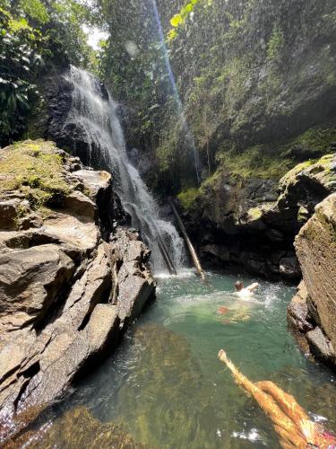 a person in a pool of water next to a waterfall at Ti kaz COCO DOUCEUW sea view in Sainte-Anne