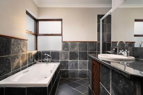 a bathroom with a tub and a sink at Premier Hotel Roodevalley in Pretoria