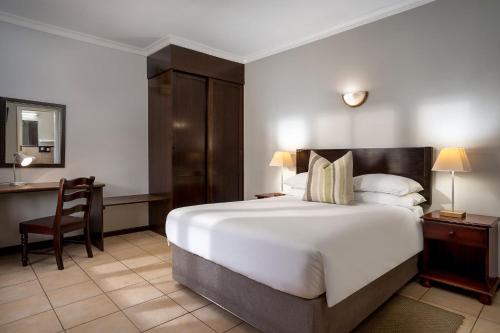 a hotel room with a large bed and a desk at Premier Hotel Roodevalley in Pretoria