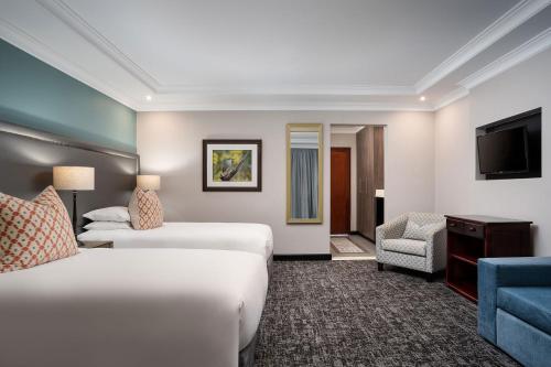 a hotel room with two beds and a television at Premier Hotel Roodevalley in Pretoria