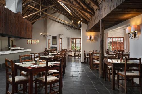 una sala da pranzo con tavoli e sedie in legno di Premier Hotel Roodevalley a Pretoria