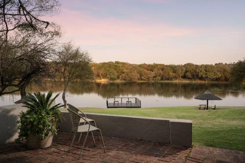 a couple of chairs sitting in front of a lake at Premier Hotel Roodevalley in Pretoria