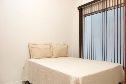 a bed in a room with a large window at 104-FLAT-Espaço, conforto. É disso que você precisa! in Anápolis