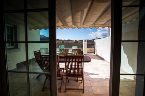 une salle à manger avec une table et des chaises sur une terrasse dans l'établissement Orquídea Holiday Modern House, à Mogán