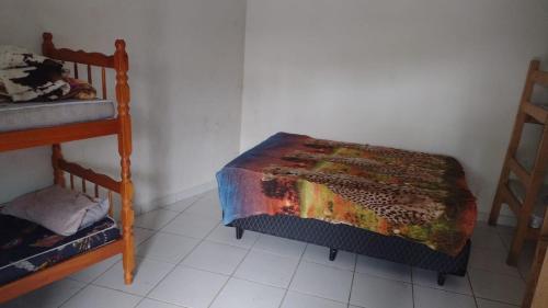 a bedroom with a bed and two chairs and a table at Colônia Virtual Net in Itanhaém
