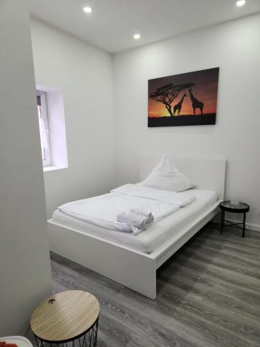 - un lit blanc dans une chambre avec une photo sur le mur dans l'établissement Klein & Fein Aurachtal, à Neundorf