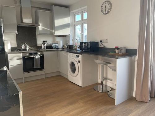 a kitchen with a washing machine and a washer at Premium flat! Enjoy luxurious white Egyptian bedding near Gants Hill Station, Ilford, London in Wanstead