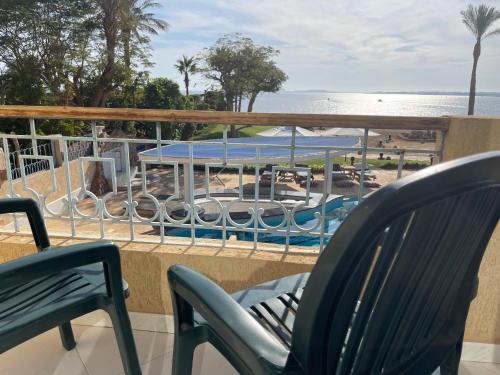 a balcony with chairs and a table and a beach at Ras Katy Sunset Views in Sharm El Sheikh