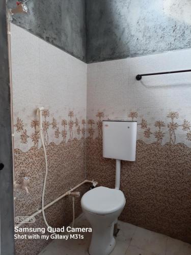 baño con aseo blanco en una habitación en Moongil Kudil en Yelagiri