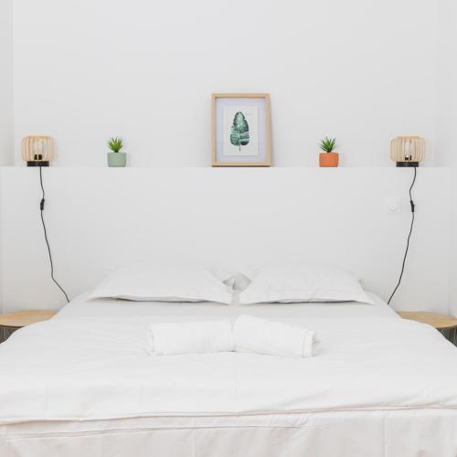 een witte slaapkamer met een wit bed en 2 verlichting bij LA SUITE SEPT LE BRAS DOR in Boulogne-sur-Mer