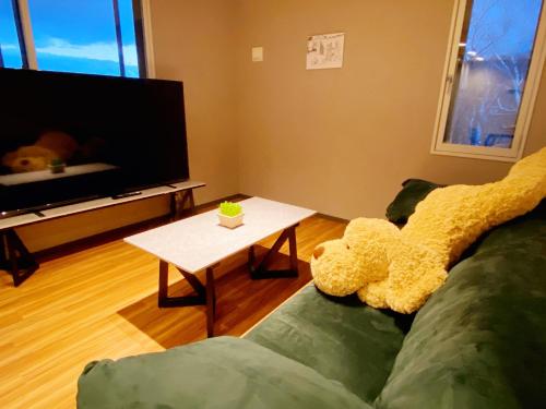 a living room with a teddy bear sitting on a couch at Q FOX GMG HOTEL in Kutchan