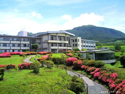 a building with a garden of flowers in a park at Senomoto Kogen Hotel in Minamioguni