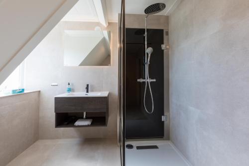 La salle de bains est pourvue d'une douche et d'un lavabo. dans l'établissement Hello Zeeland - Appartement Brouwerijweg 43-2, à Domburg