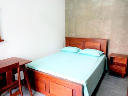 a bedroom with a bed with a wooden frame and two tables at Li's Apartment in Kottawa