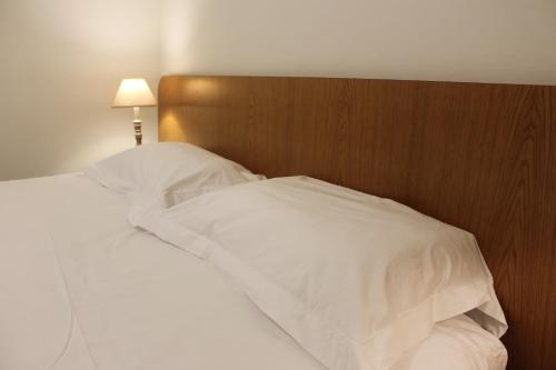 a bed with white sheets and a wooden headboard at La Bullote - Gîtes - Paris Roissy CDG in Villeneuve-sous-Dammartin