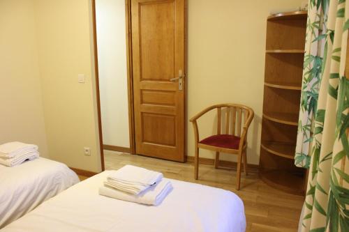a room with two beds and a chair and a door at La Bullote - Gîtes - Paris Roissy CDG in Villeneuve-sous-Dammartin