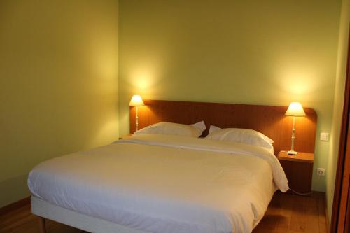 a bedroom with a large white bed with two lamps at La Bullote - Gîtes - Paris Roissy CDG in Villeneuve-sous-Dammartin