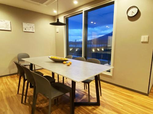 a dining room table with chairs and a large window at Q FOX GMG HOTEL in Kutchan