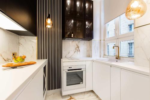 une cuisine avec des armoires blanches et un évier dans l'établissement Sumptuous apartment - 1BR-6P - Bourse, à Paris