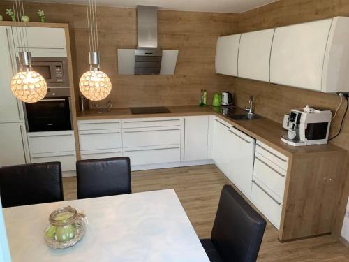 une cuisine avec des placards blancs et une table avec des chaises dans l'établissement Appartement Centerbase Salzburgerland, à Sankt Veit im Pongau