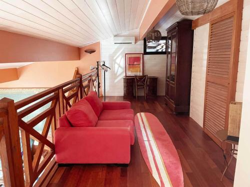 a living room with a red couch and a staircase at Yamina Lodge in Cap-Ferret