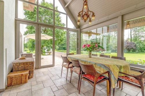 a dining room with a table and chairs and windows at Luxury Raesborre Domain in Leuven