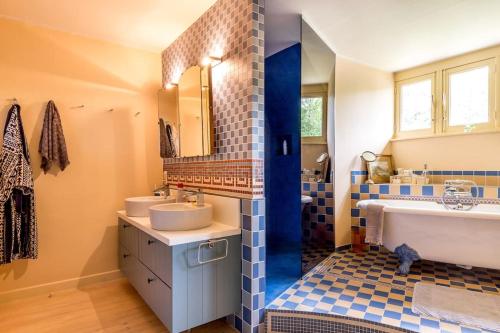 een blauwe en witte badkamer met 2 wastafels en een bad bij Luxury Raesborre Domain in Leuven