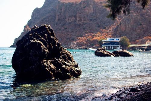 a large rock in the water next to a beach at Pantheon Studios in Léntas