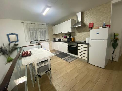 a kitchen with a table and a white refrigerator at Ninho D'Arara in Tondela
