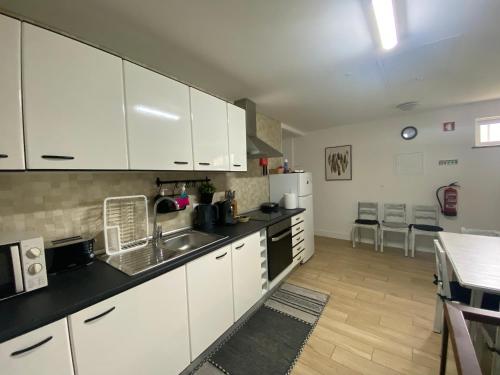 a kitchen with white cabinets and a counter top at Ninho D'Arara in Tondela
