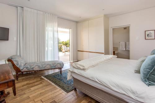 a bedroom with a bed and a chair and a window at Far Horizons Camps Bay in Cape Town