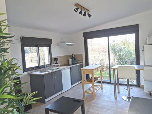 een keuken met grijze kasten en een tafel en een tafel bij Studio indépendant, 10min Avignon in Pujaut