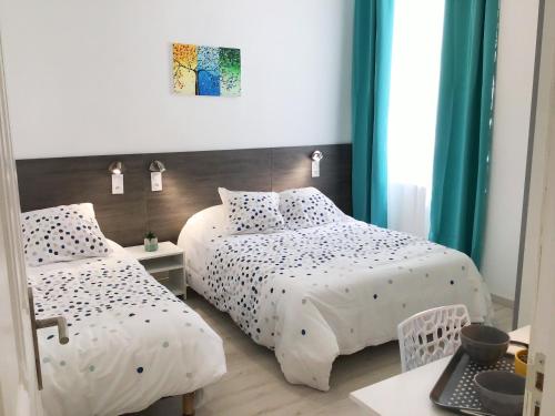 two beds in a room with green curtains at Appartement Lumea 80 m2 climatisé parking proche Sanctuaires in Lourdes