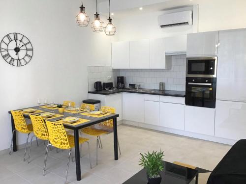 a kitchen with a dining table and yellow chairs at Appartement Lumea 80 m2 climatisé parking proche Sanctuaires in Lourdes