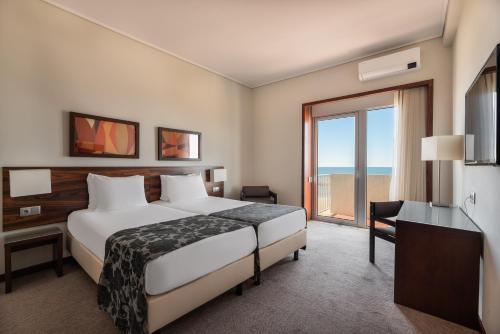 a hotel room with a bed and a large window at Exe Praia Golfe in Espinho