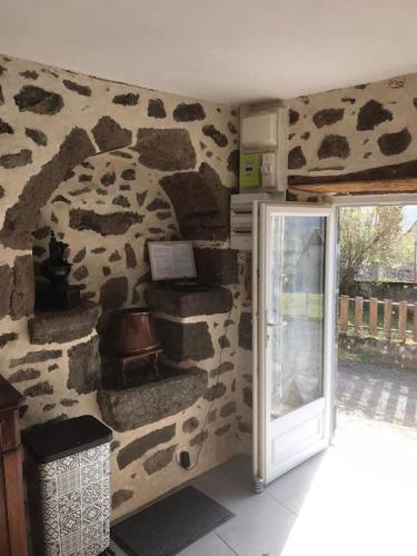 Cette chambre est dotée d'un mur en pierre et d'une porte. dans l'établissement Maison auvergnate traditionnelle récemment rénovée, à La Roquevieille