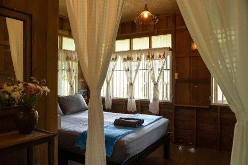 Schlafzimmer mit einem Bett und einem Fenster mit Vorhängen in der Unterkunft Art House at Chiangdao - Moon House in Chiang Dao